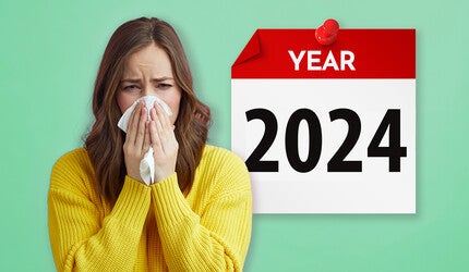 A woman blowing her nose in front of a 2024 calendar.