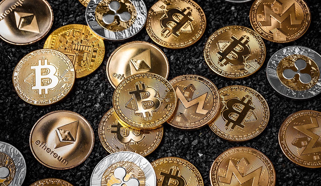 A stack of cryptocurrencies like Bitcoin and Ethereum represented as gold coins. 
