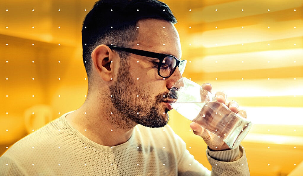 A man drinking a glass of water, shrouded in gold light