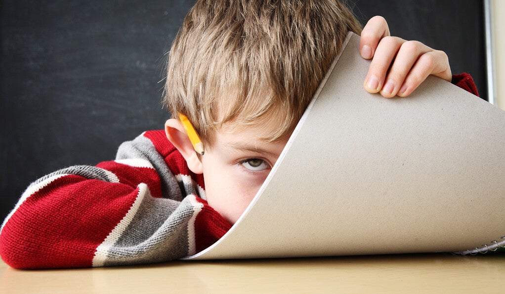 A child peeking from behind a notepad