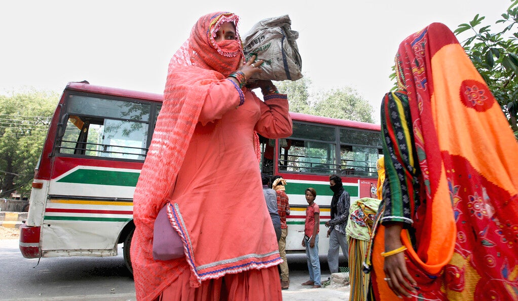 Migrants workers from Madhya Pradesh unload their belongings from a bus