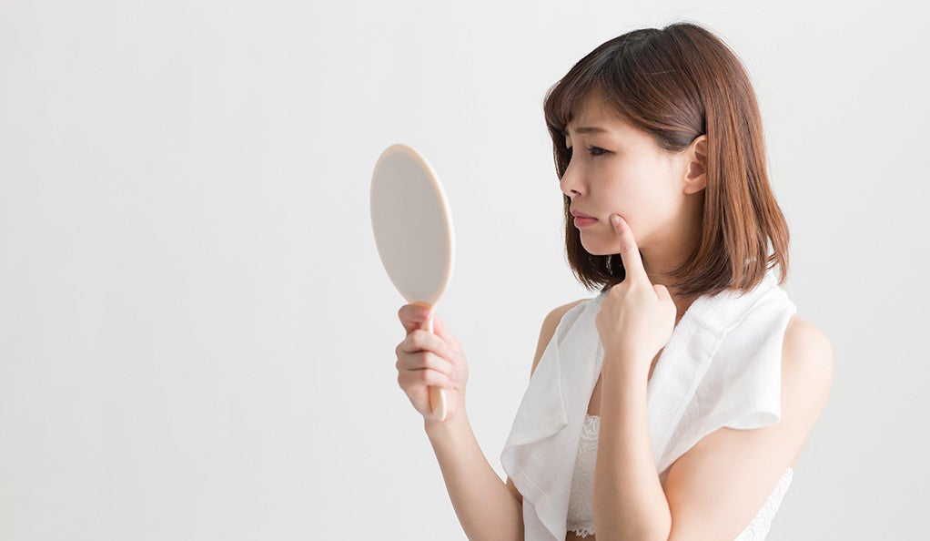 A young woman looking at herself in the mirror, pouting