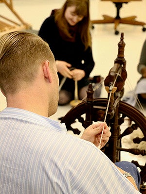 Workshop participants tried various methods of spinning wool, including with hand spindles and with a spinning wheel. 