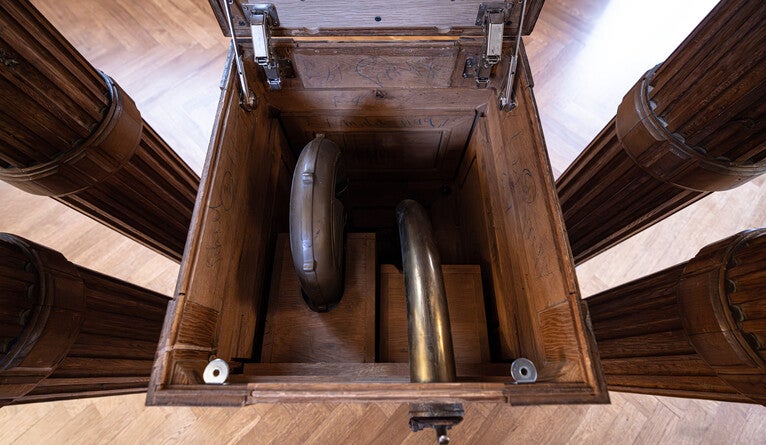 A pneumatic message delivery tube inside a wooden box