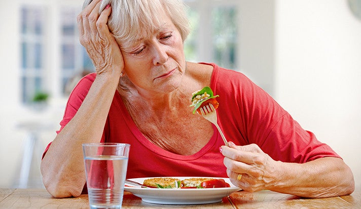 A women looking unhappily at a forkful of salad.