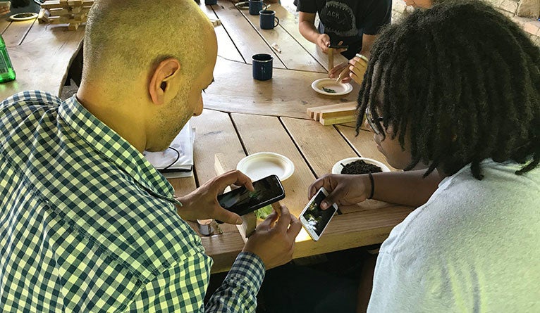 Ziad Ganim and a Pathways student look through homemade smartphone microscopes at Yale Farm.