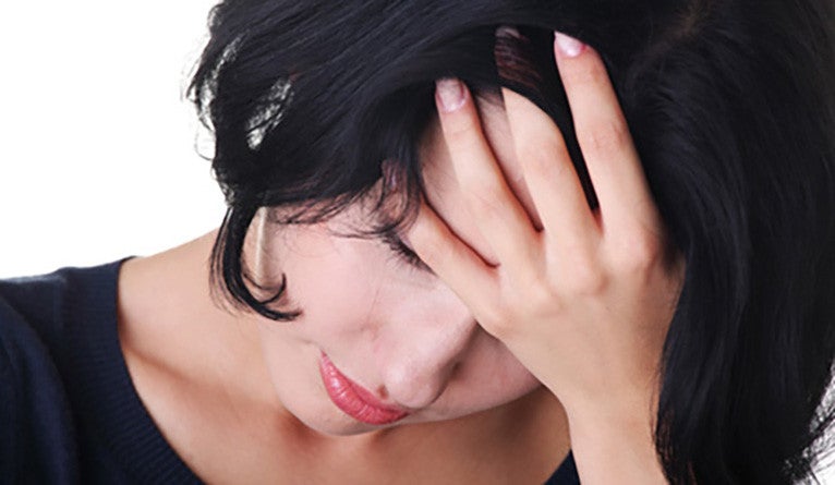 A depressed woman holding her head in her hands.