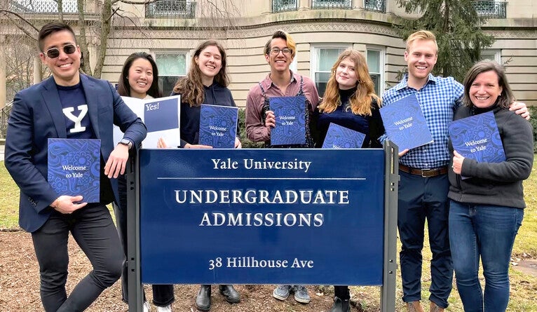 Yale admissions staff pose with welcome packets for the newly admitted members of the Class of 2026.
