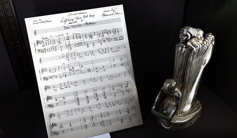 The original music for “Lift Ev’ry Voice and Sing,” alongside a miniature of a statue inspired by the hymn