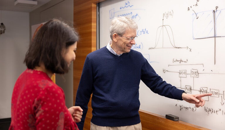 Girvin talks shop at a whiteboard at the Yale Quantum Institute.