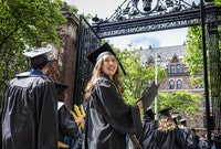 A student looks back and smiles before processing through Porter Gate at Commencement.